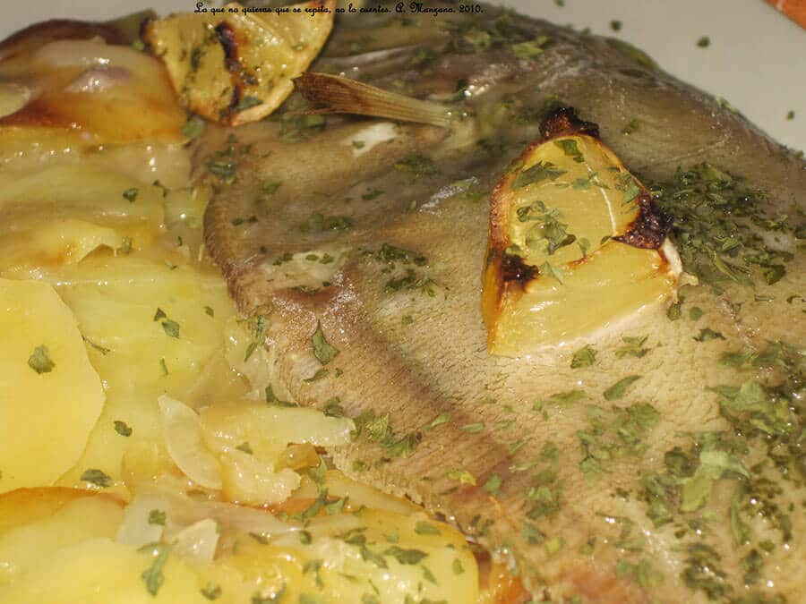 Filetes de gallo al horno servidos con patatas panadera, rodajas de limón asado y espolvoreados con perejil fresco.